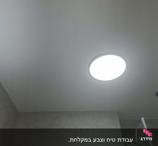תקרת חדר אמבטיה צבועה בלבן עם גוף תאורה עגול